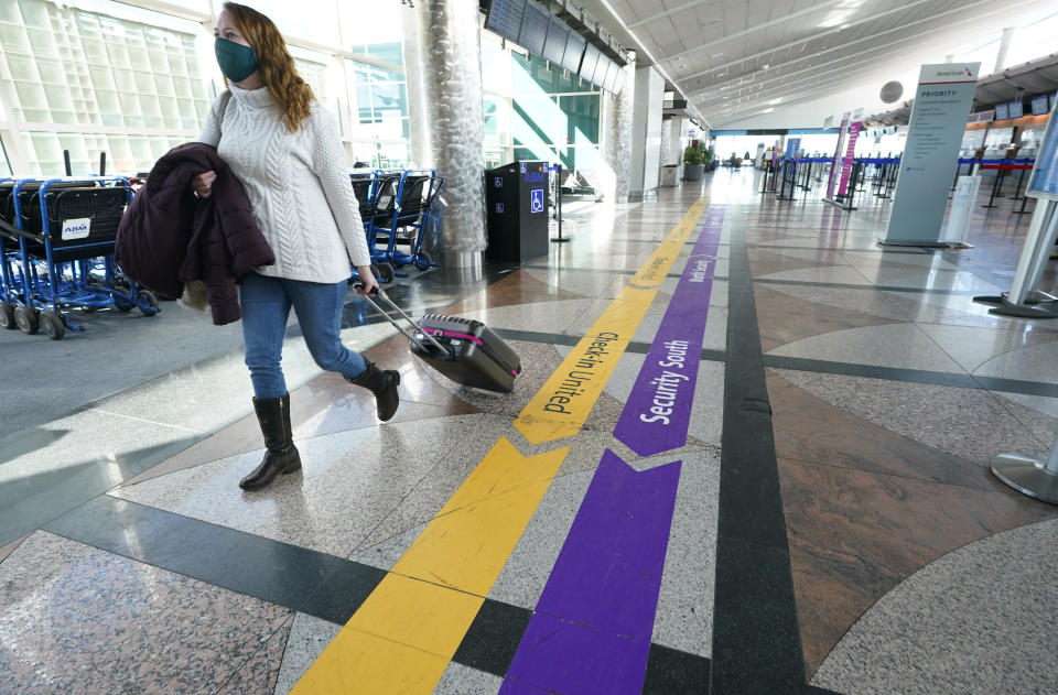 FILE - In this Feb. 18, 2021, file photo, a lone traveler wears a face covering while hurrying through a near-empty check-in counter area in the main terminal of Denver International Airport, in Denver. At least for now, U.S. health authorities say after being vaccinated, people should follow the same rules as everybody else about wearing a mask, keeping a 6-foot distance and avoiding crowds even after they’ve gotten their second vaccine dose. (AP Photo/David Zalubowski, File)