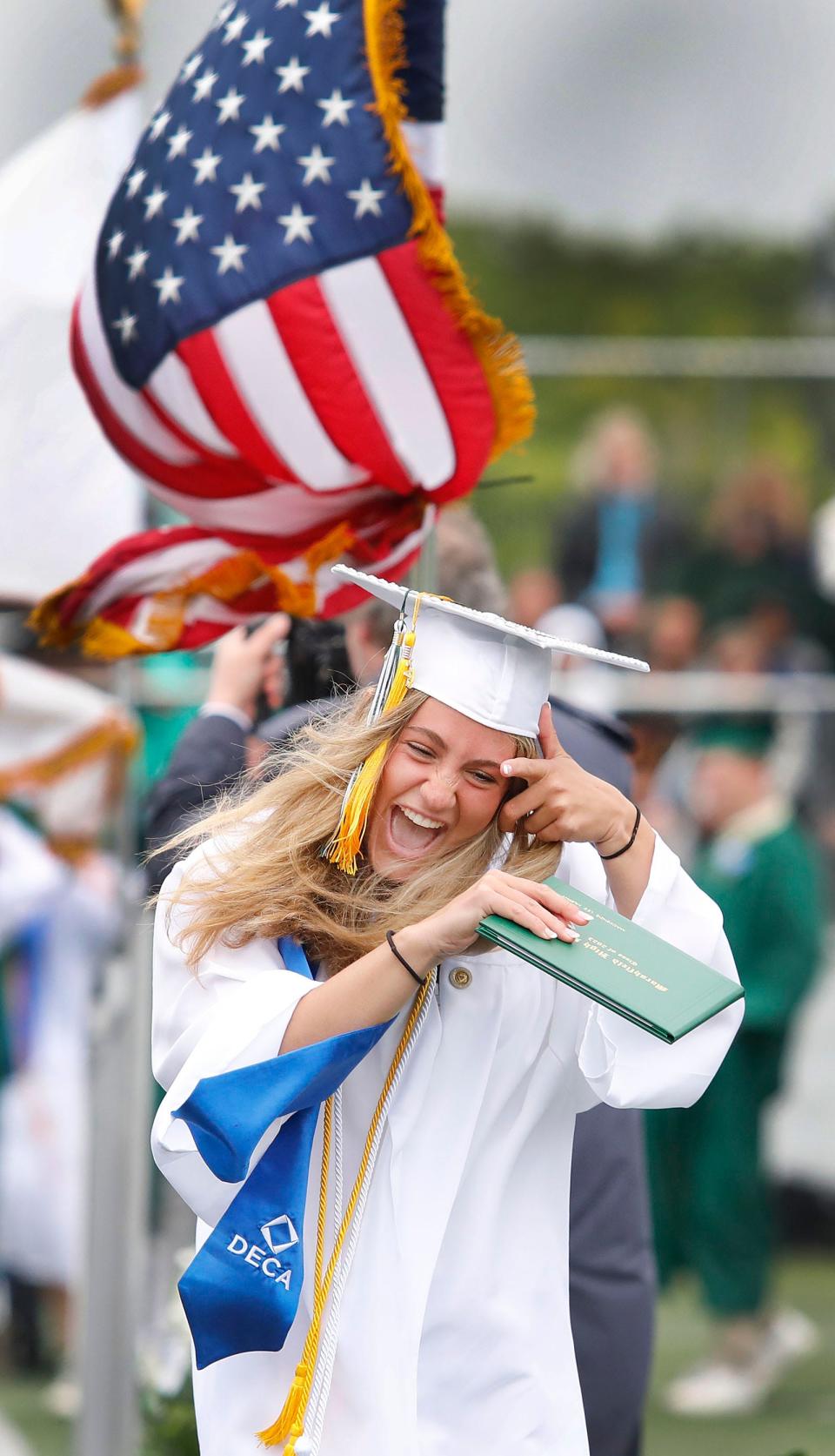 Mackenzie Murphy tries to hold on to her cap and diploma in the wind.
