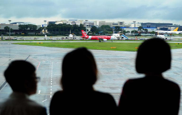 People watch as an AirAsia plane taxis on the tarmac after landing at Changi international airport in Singapore