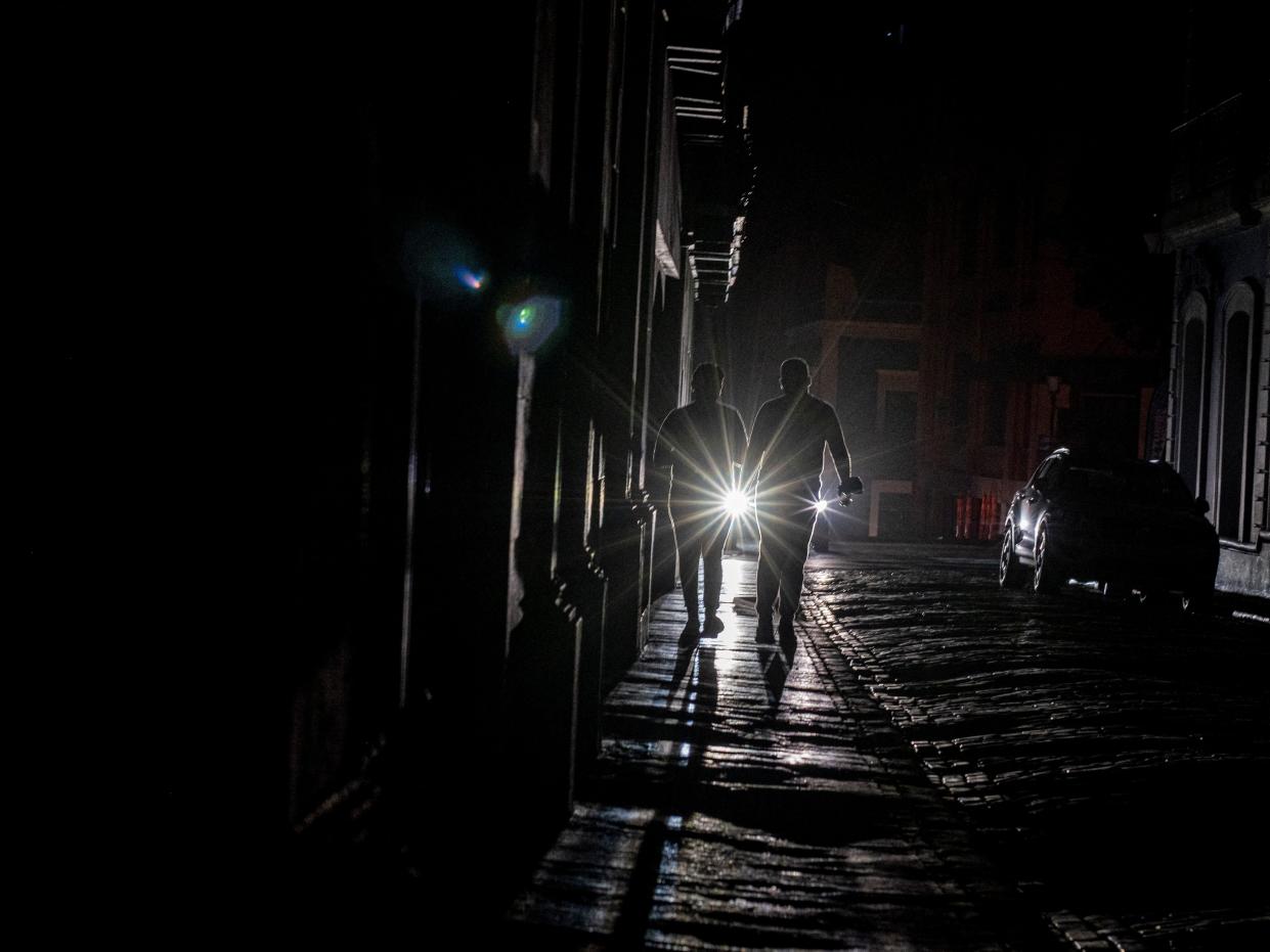 Puerto Ricans walk along a dark San Juan street after the major blackout on April 6, 2022.