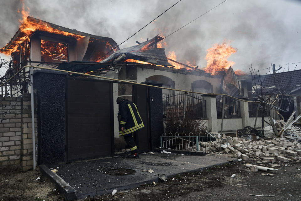 A firefighter stands at a burning house hit by the Russian shelling in Kherson, Ukraine, on the Orthodox Christmas Eve Friday, Jan. 6, 2023. (AP Photo/LIBKOS)