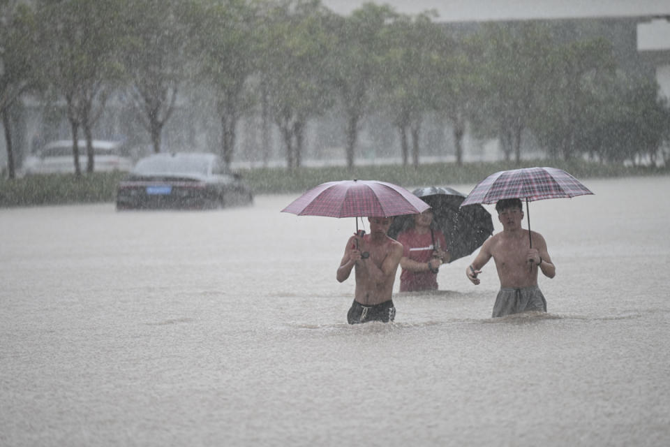 2021年7月20日，河南省鄭州市，人們在鄭州火車站附近的洪水中行走。