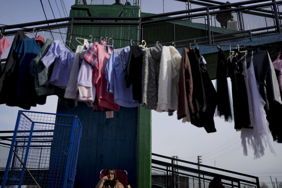 Prendas de segunda mano se exhiben en un tendedero improvisado en un mercado donde la gente puede comprar o intercambiar productos en las afueras de Buenos Aires, Argentina, el miércoles 10 de agosto de 2022. (AP Foto/Natacha Pisarenko)