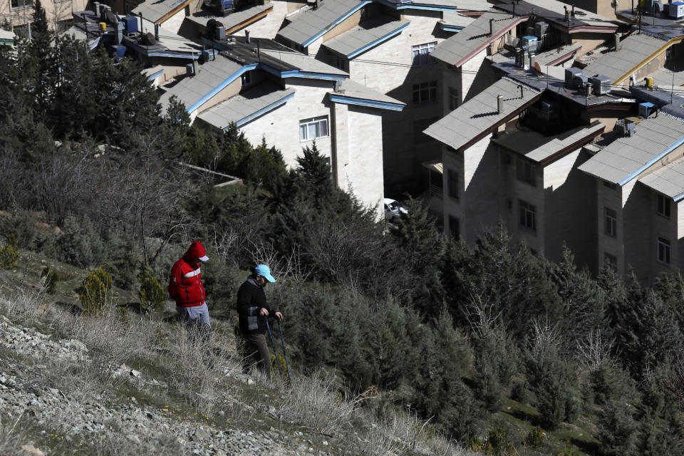 Hikers descend from a foothill of the Alborz mountain range, overlooking the capital Tehran, as they spend New Year, or Nowruz, holidays, Iran, Tuesday, March 31, 2020. In recent days, Iran which is battling the worst new coronavirus outbreak in the region, has ordered the closure of nonessential businesses and banned intercity travels aimed at preventing the virus' spread. Public parks are closed as well as sport and recreational clubs which were shut previously. (AP Photo/Vahid Salemi)