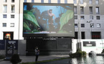 A giant screen streams a Moschino fashion live show presenting the women's Fall Winter 2021-22 collection, unveiled during the Fashion Week in Milan, Italy, Thursday, Feb. 25, 2021. (AP Photo/Antonio Calanni)