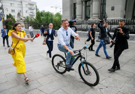 Radical Party leader Oleh Lyashko speaks with journalists as he rides a bicycle after new President Volodymyr Zelenskiy held consultations with lawmakers, near the Presidential Administration headquarters in Kiev, Ukraine May 21, 2019. REUTERS/Gleb Garanich