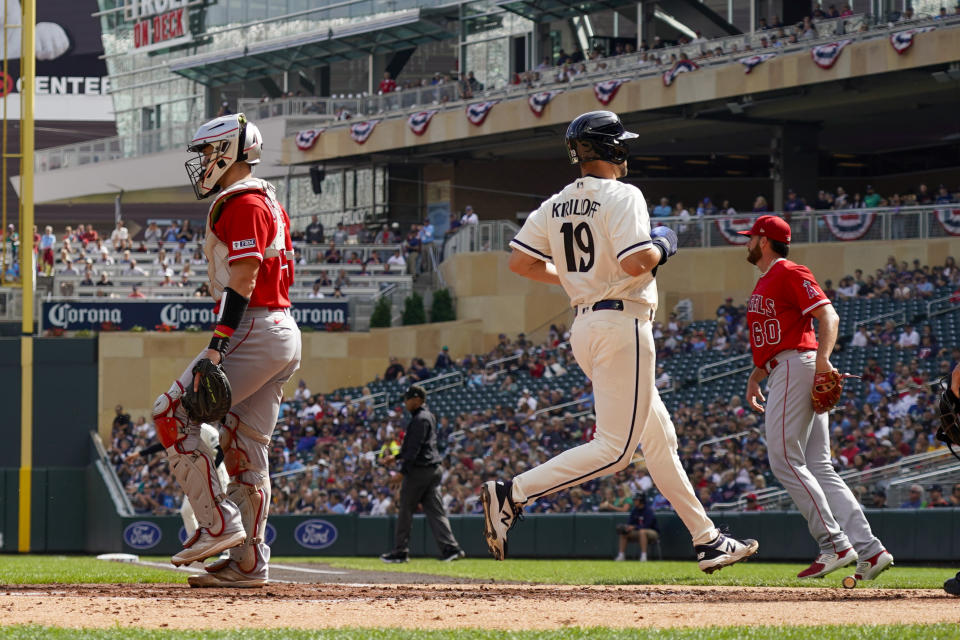 Minnesota Twins' Alex Kirilloff (19) runs past Los Angeles Angels catcher Logan O'Hoppe, left, and pitcher Andrew Wantz, right, as he scores on a Trevor Larnach single during the second inning of a baseball game Sunday, Sept. 24, 2023, in Minneapolis. (AP Photo/Craig Lassig)