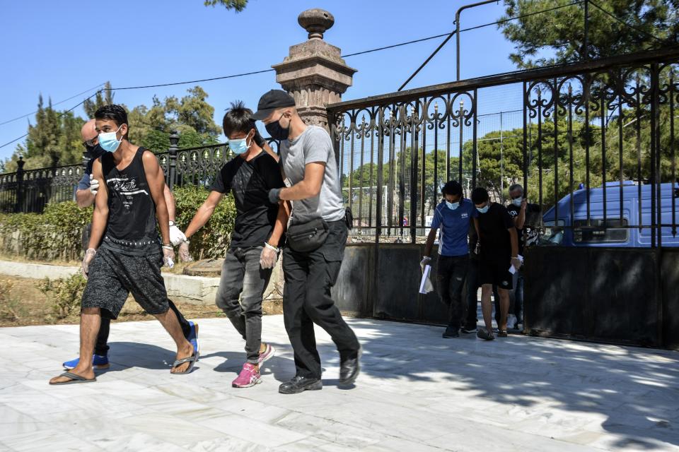 Suspects, all from Afghanistan escorted by plain clothes policemen and wearing face masks, arrive at a court in Mytilene, the capital of the northeastern Aegean island of Lesbos, Greece, Wednesday, Sept. 16, 2020. The government says the fires in Moria refugee camp were set deliberately by the Afghan migrants protesting a coronavirus lockdown, and authorities on Tuesday announced the arrests of six suspect, include two 17-year-olds, in the case. (AP Photo/Panagiotis Balaskas)