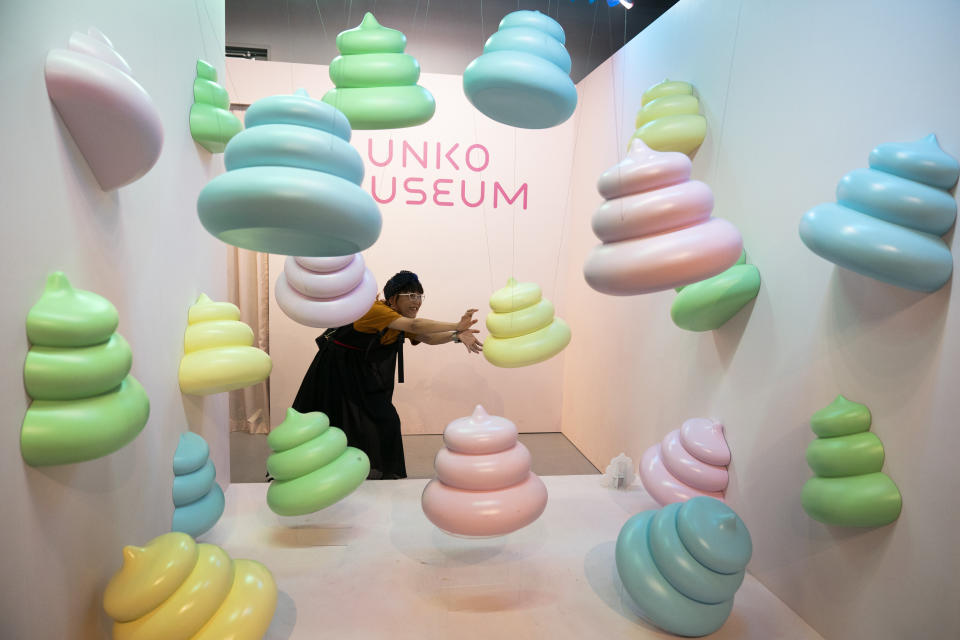 In this Tuesday, June 18, 2019, photo, a woman jokingly poses with large poop-shaped figurines at the Unko Museum in Yokohama, south of Tokyo. In a country known for its cult of cute, even poop is not an exception. A pop-up exhibition at the Unko Museum in the port city of Yokohama is all about unko, a Japanese word for poop. The poop installations there get their cutest makeovers. They come in the shape of soft cream, or cupcake toppings. (AP Photo/Jae C. Hong)
