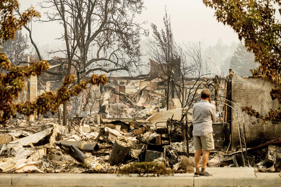 A man examines residences destroyed by the Almeda Fire at the Parkview Townhomes in Talent, Ore., on Wednesday, Sept. 16, 2020. (AP Photo/Noah Berger)