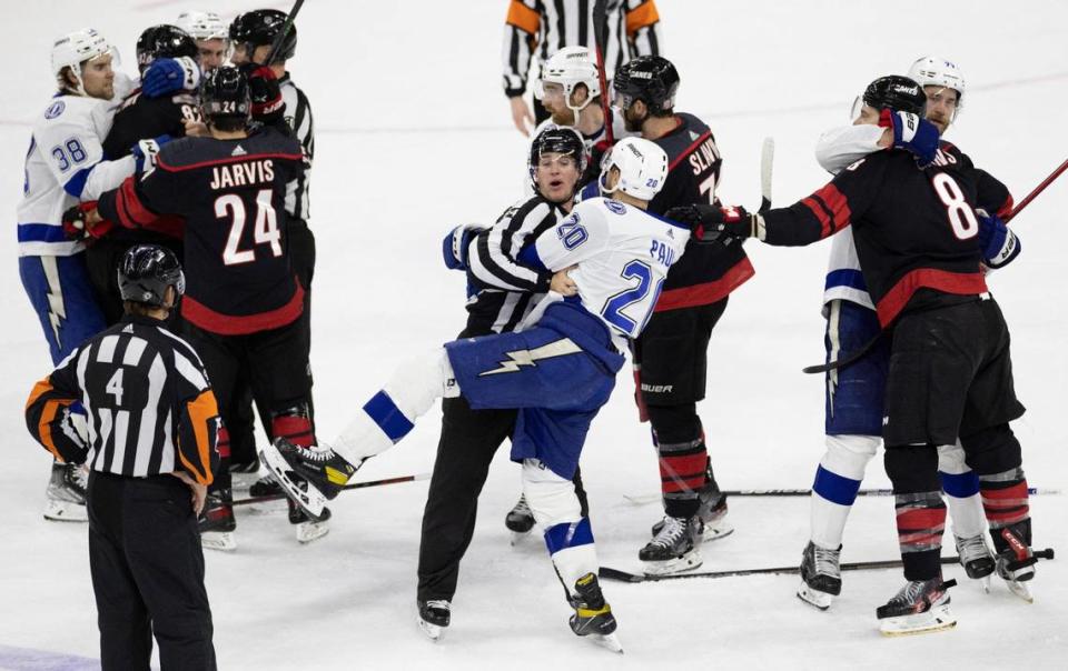 Official Ryan Jackson (84) separates Tampa’s Nicholas Paul (20) from a fight between the Hurricanes and the Lightning during the second period on Tuesday, March 28, 2023 at PNC Arena in Raleigh, N.C.