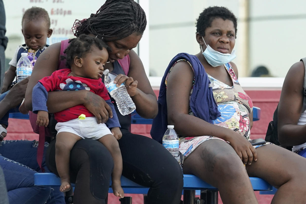 Migrants, mostly from Haiti, wait for a bus after they were processed and released after spending time at a makeshift camp near the International Bridge, Sunday, Sept. 19, 2021, in Del Rio, Texas. President Joe Biden's administration is nearing a final plan to expel many of the thousands of Haitian migrants who have suddenly crossed into a Texas border city from Mexico and to fly them back to their Caribbean homeland. (AP Photo/Eric Gay)