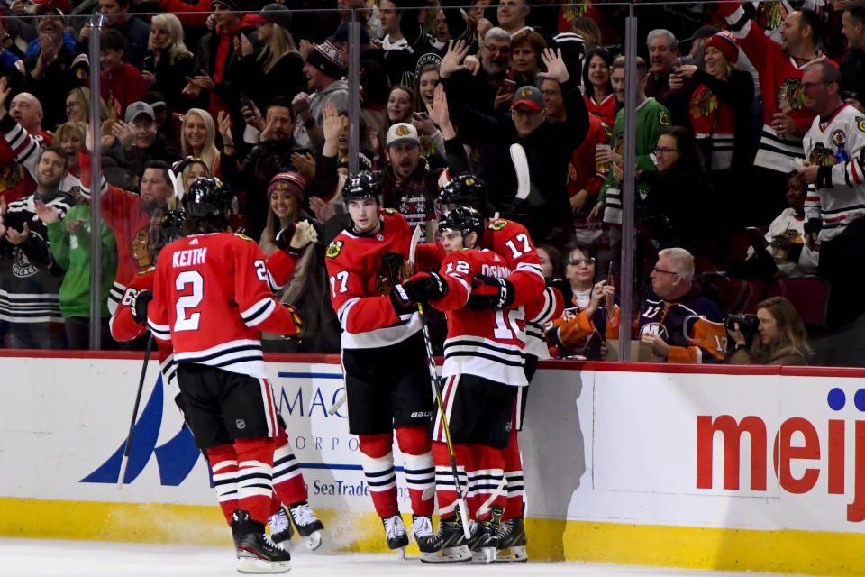 Chicago Blackhawks left wing Alex DeBrincat (12) celebrates with teammates after scoring a goal against the New York Islanders during the first period of an NHL hockey game Friday, Dec. 27, 2019, in Chicago. (AP Photo/Matt Marton)