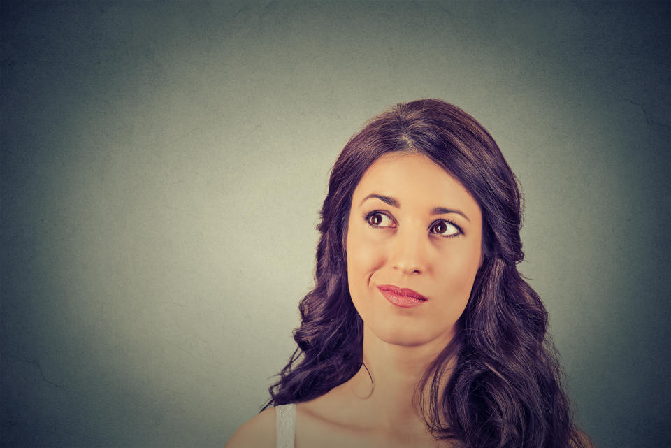 Closeup funny confused skeptical woman thinking planning looking up isolated on gray wall background copy space above head. Human face expression emotion feeling body language, perception reaction