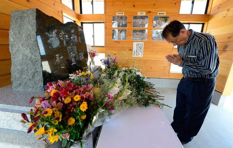 A tourist prays for victims in front of a monument in Rikuzentakata, Japan, on July 20, 2013. Though the city was nearly wiped off the map by the 2011 tsunami, visitors are flocking back to see the devastation, the latest example of a phenomenon dubbed "dark tourism" where holidaymakers pay to witness the aftermath of others' misery