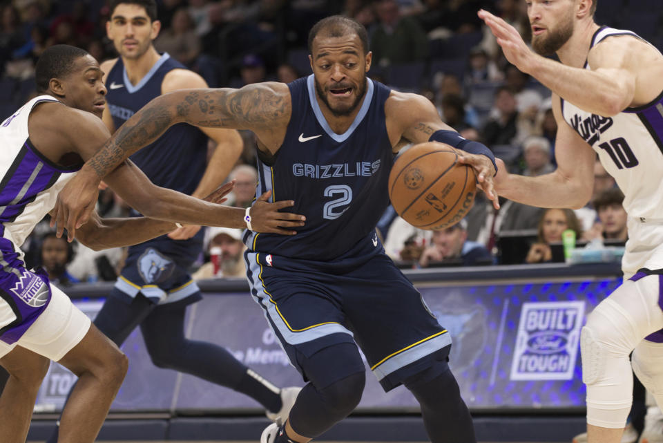 Sacramento Kings guard De'Aaron Fox, left, and forward Domantas Sabonis (10) defend against Memphis Grizzlies forward Xavier Tillman (2) in the first half of an NBA basketball game Monday, Jan. 29, 2024, in Memphis, Tenn. (AP Photo/Nikki Boertman)