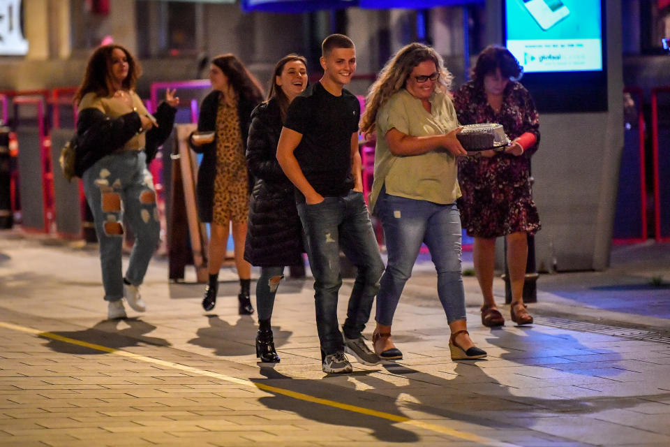 A group of young people walk through Cardiff city centre at night. A ban on groups of more than six people meeting indoors in Wales, including pubs and restaurants, is expected to be announced later today as ministers try to tackle the rising number of coronavirus cases across the UK.