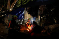 Migrants, part of a caravan of thousands from Central America trying to reach the United States, take shelter as they warm themselves by a fire on a street in Tijuana, Mexico, December 7, 2018. REUTERS/Mohammed Salem