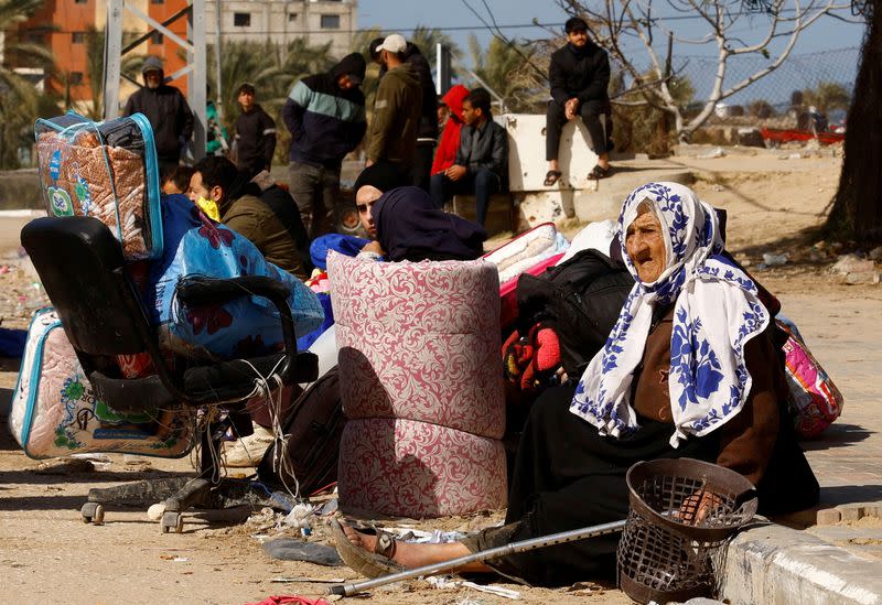 Palestinos, que huyen de Jan Yunis, descansan junto a la carretera con sus pertenencias en marcha hacia Rafah