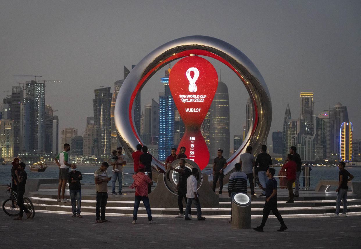 FILE - People gather around the official countdown clock showing remaining time until the kick-off of the World Cup 2022, in Doha, Qatar, Thursday, Nov. 25, 2021. Fans going to the World Cup in Qatar must show a negative COVID-19 test when they arrive as part of the host nation’s rules to combat COVID-19, organizers said Thursday, Sept. 29, 2022. (AP Photo/Darko Bandic, File)