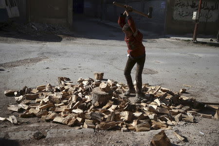 A boy cuts firewood along a street in the Douma neighbourhood of Damascus, Syria February 9, 2016. REUTERS/Bassam Khabieh