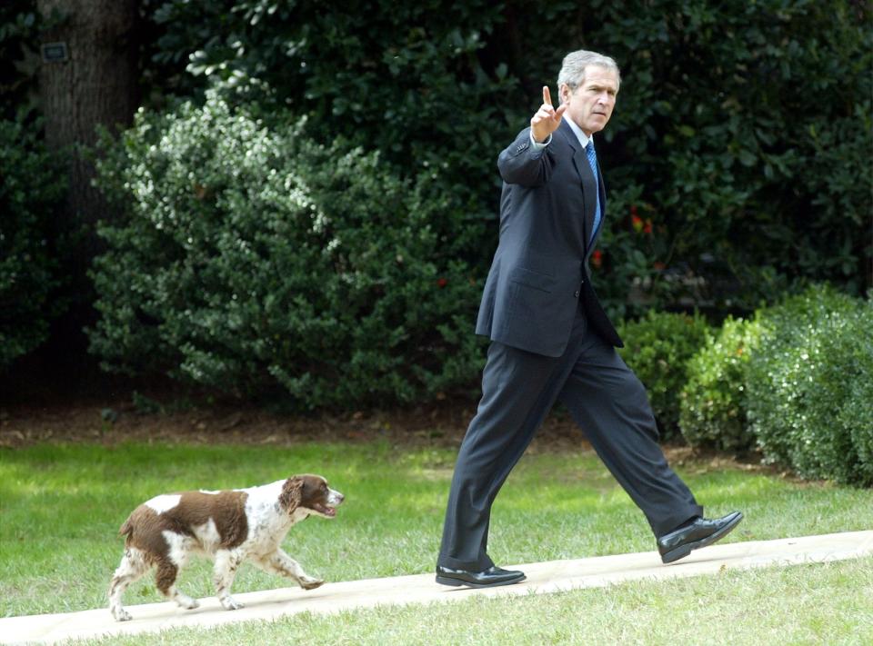 President George W. Bush waves as he walks toward the Oval Office with his dog Spot in 2002.