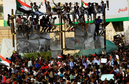 Sudanese demonstrators climb on a torn billboard as they chant slogans, during the sit-in protest outside Defence Ministry in Khartoum, Sudan April 18, 2019. REUTERS/Stringer
