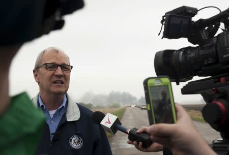 U.S. Representative Kevin Cramer, (R-ND) speaks to the media while smoke from the wreckage of several oil tanker cars that derailed in a field near the town of Heimdal, North Dakota, U.S. billows behind him on May 6, 2015. REUTERS/Andrew Cullen/File Photo