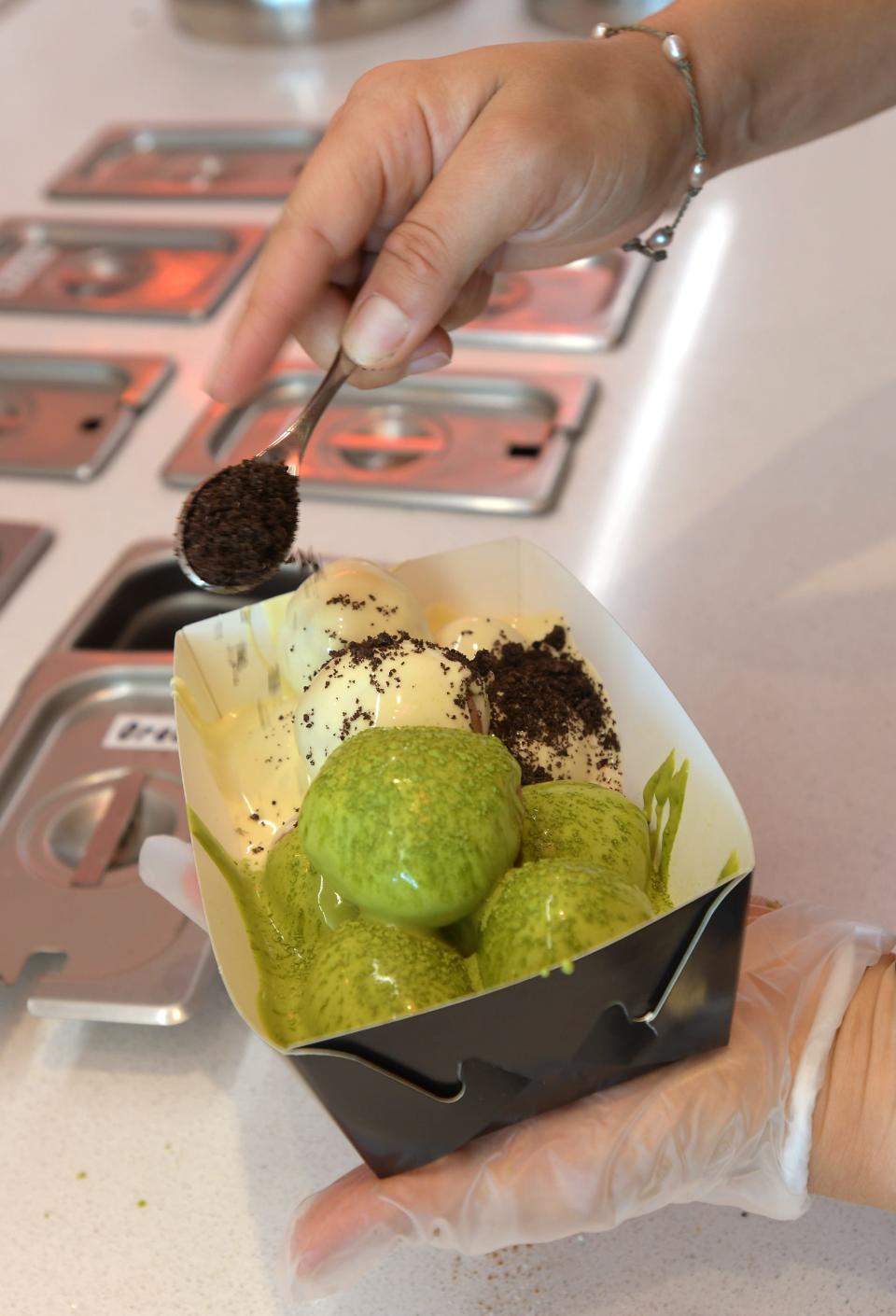 Crushed Oreos are sprinkled on white chocolate Cookies & Cream doughnuts in a mixed box with Love U So Matcha doughnuts drizzled with Matcha infused white chocolate at Lukumades, a new doughnut shop in Jacksonville Beach.