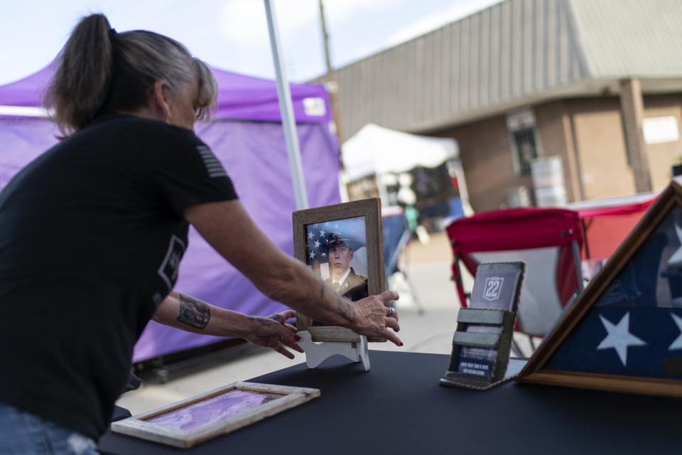 Barbie Rohde sets up a photo of her son, Army Sgt. Cody Bowman, at a festival while volunteering for Mission 22, a nonprofit that is focused on ending military and veteran suicide, Saturday, June 10, 2023, in Jacksonville, Texas. Bowman, who took his own life in 2019, declared at 4 years old he would be “an Army guy” and never changed his mind. People ask her now, if she could turn back time, would she try to stop him. She says no. It’s what he’d always wanted. (AP Photo/David Goldman)