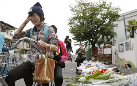 A woman in a bicycle cries in front of floral tributes to a victim of yesterday's earthquake in Takatsuki, Osaka prefecture, western Japan, in this photo taken by Kyodo June 19, 2018. Mandatory credit Kyodo/via REUTERS