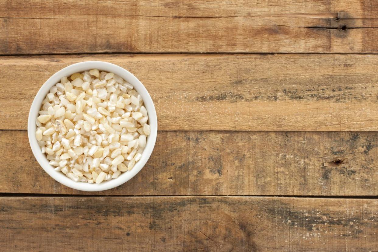 Top view of white bowl full of split white corn over wooden table