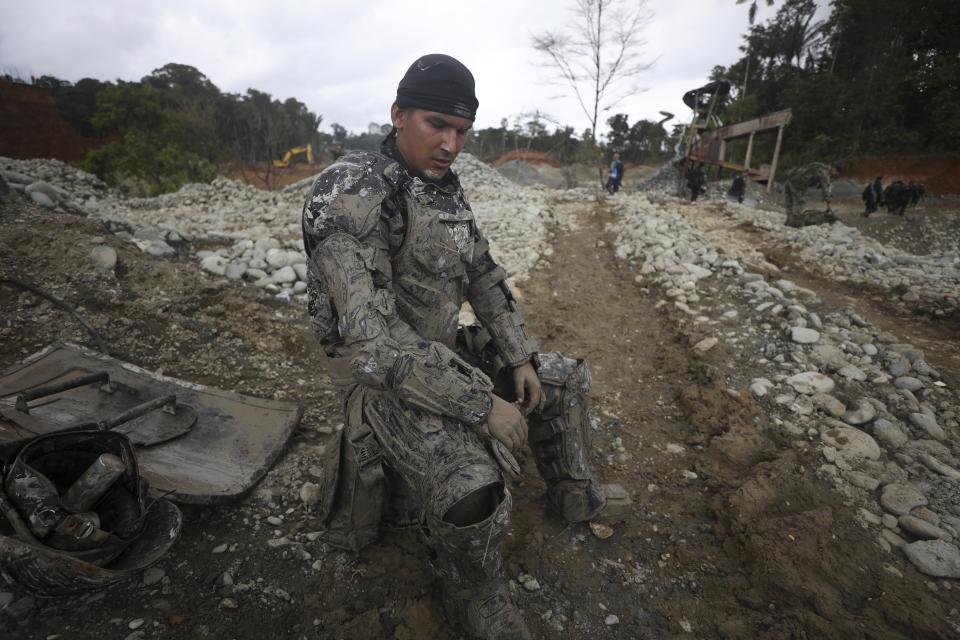 Covered in mud, a National Police officer rests momentarily from destroying machinery at an illegal gold mine as part of the Armed Forces' "Operation Guamuez III" in Magui Payan, Colombia, Tuesday, April 20, 2021. Illegal gold mining is common in Colombia, especially wildcat mines in poverty-stricken areas dominated by criminal gangs with little state presence. (AP Photo/Fernando Vergara)