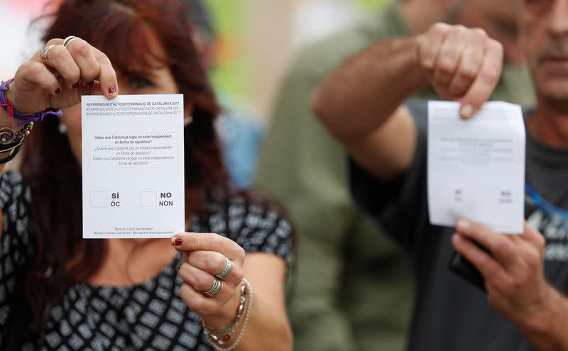 Deux personnes montrent des bulletins de vote, un jour avant le réferendum interdit sur l'indépendance de la Catalogne. Le pouvoir central est déterminé à empêcher la tenue du référendum. Des milliers de policiers ont été déployés en renfort des forces locales. /Photo prise le 30 septembre 2017/REUTERS/Yves Herman