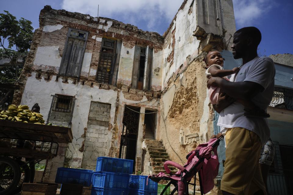 Residents walk past dilapidated mansion on Villegas Street in Havana, Cuba, Thursday, Oct. 5, 2023. The two-story building, which houses six families, is one of many, once luxurious houses that in recent years have partially collapsed or suffered visible damage. (AP Photo/Ramon Espinosa)