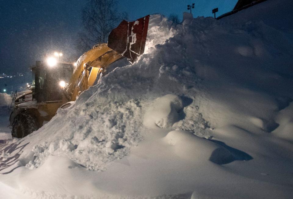 Workers use heavy machines to clear huge masses of snow from the streets of the village of Sankt Anton am Arlberg. Image: Getty