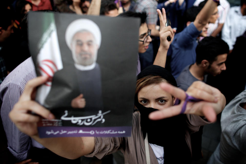 An Iranian woman flashes the sign for victory as she holds a portrait of moderate presidential candidate Hassan Rouhani during celebrations for his victory in the Islamic Republic's presidential elections in downtown Tehran on June 15, 2013. (BEHROUZ MEHRI/AFP/Getty Images)