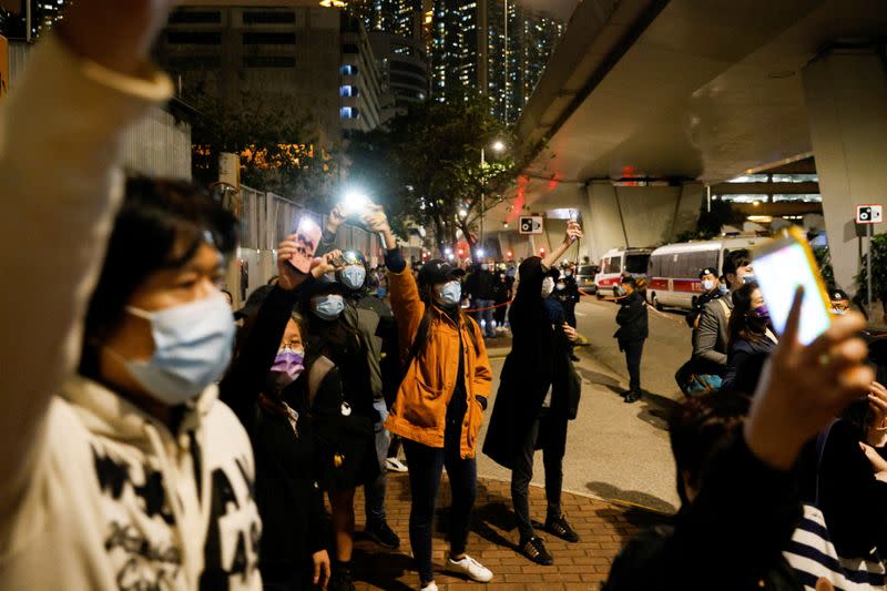 Supporters of pro-democracy activists wave flashlights as a prison van which is carrying some of 47 pro-democracy activists charged with national security law leaves West Kowloon Magistrates' Courts, in Hong Kong