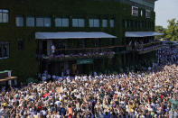 Serbia's Novak Djokovic holds the winners trophy to show to fans gathered outside Centre Court as he celebrates after beating Australia's Nick Kyrgios to win the final of the men's singles on day fourteen of the Wimbledon tennis championships in London, Sunday, July 10, 2022. (AP Photo/Alberto Pezzali)