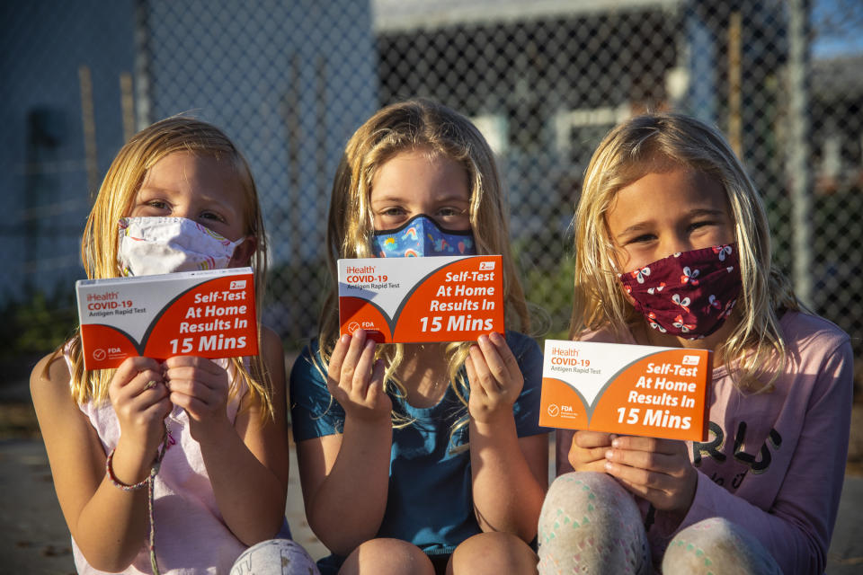 Girls wearing masks holding COVID tests