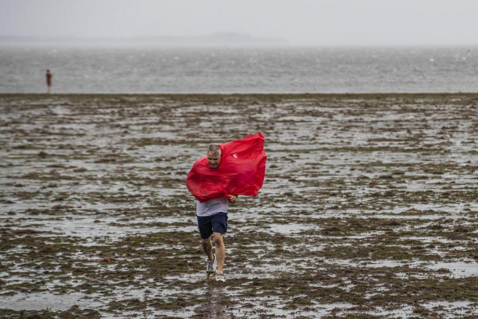 People walk in the receding waters of Tampa Bay due to the low tide from Hurricane Ian in Tampa, Fla. on Wednesday.