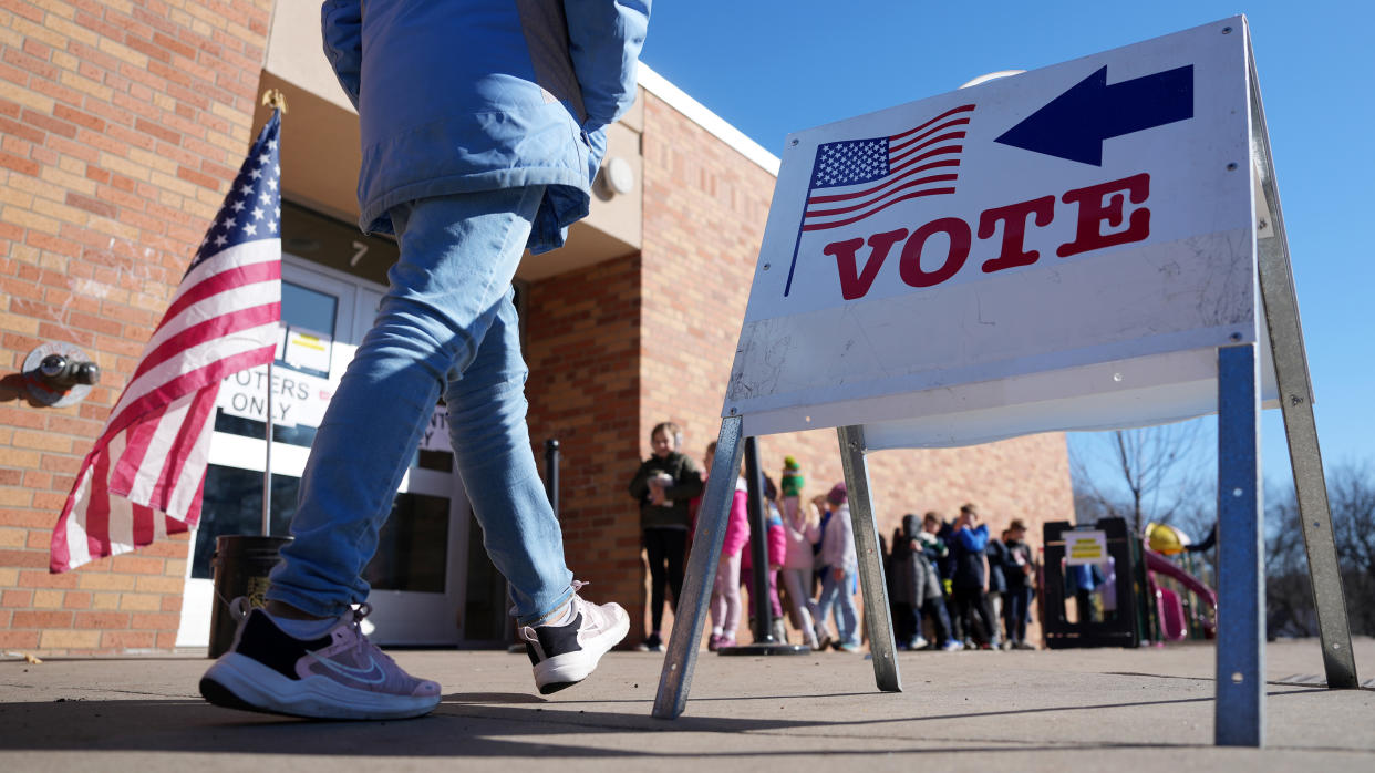 Voters walk past lines of students to cast their ballots