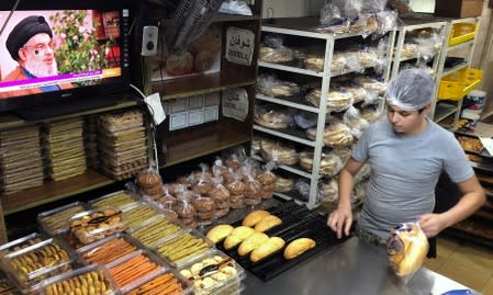 Lebanon's Hezbollah leader Sayyed Hassan Nasrallah is seen on a TV screen inside a bakery in Sidon