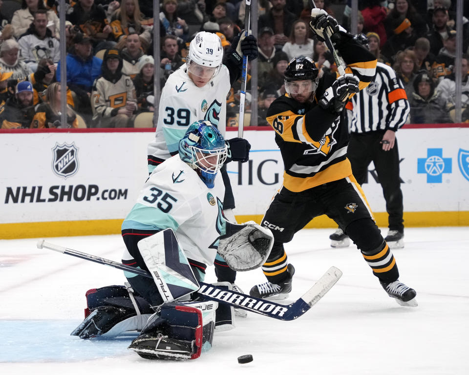 Seattle Kraken goaltender Joey Daccord (35) blocks a shot with Ryker Evans (39) defending Pittsburgh Penguins' Sidney Crosby (87) during the second period of an NHL hockey game in Pittsburgh, Monday, Jan. 15, 2024. (AP Photo/Gene J. Puskar)