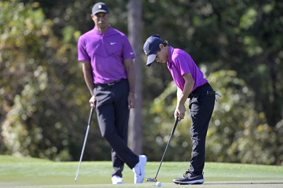 Tiger Woods watches as his son Charlie sinks a putt on the first green during the first round of the PNC Championship golf tournament, Saturday, Dec. 19, 2020, in Orlando, Fla. (AP Photo/Phelan M. Ebenhack)