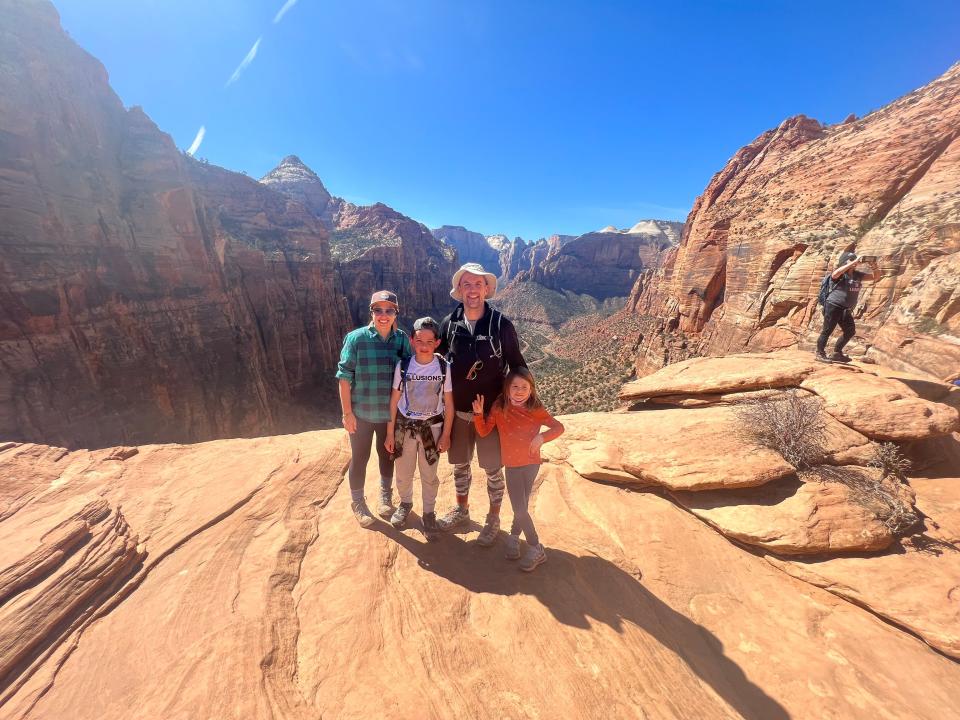 A family of four pose at a scenic overlook in a national park.