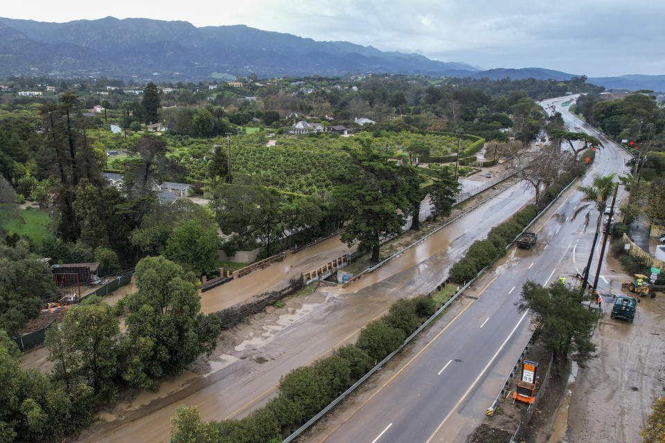 In an aerial view, a flooded area by the overflowing San Ysidro creek on Jameson Lane is seen near the closed Highway 101 in Montecito, Calif., Tuesday, Jan. 10, 2023. California saw little relief from drenching rains Tuesday as the latest in a relentless string of storms swamped roads, turned rivers into gushing flood zones and forced thousands of people to flee from towns with histories of deadly mudslides. (AP Photo/Ringo H.W. Chiu)