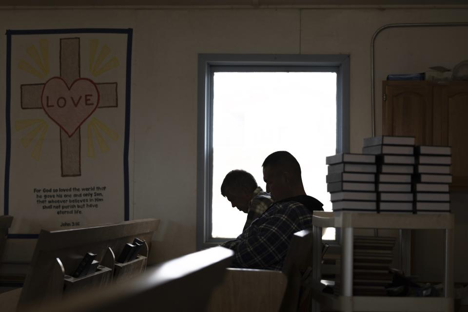 Churchgoers bow their heads during prayer inside the Akiachak Moravian Church, Sunday, Aug. 20, 2023, in Akiachak, Alaska. "Not even half a year, and people don't want to go back to the honey bucket," said Carl Ekamrak, the elder-in-charge of the church. (AP Photo/Tom Brenner)