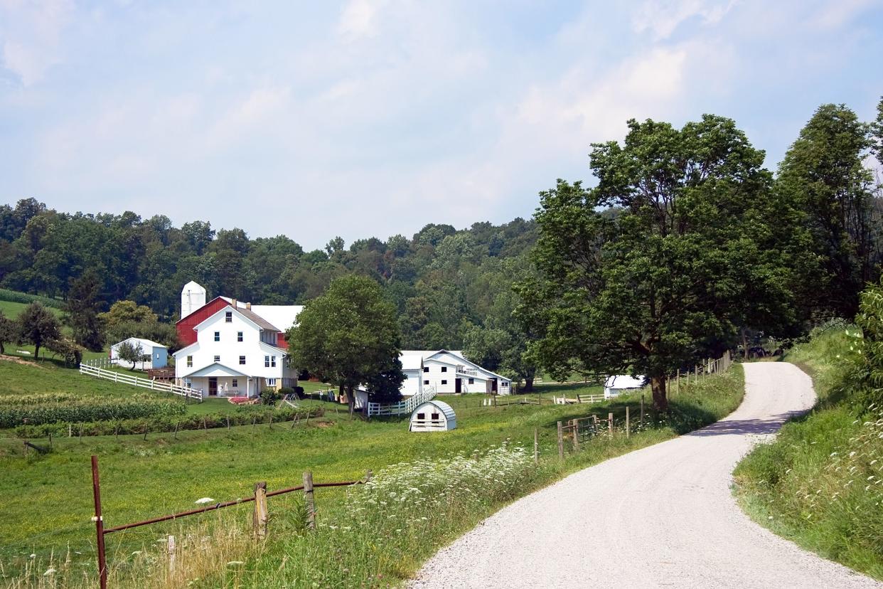 Amish Home Along a Winding Road in Holmes County, Ohio, a big house and a few smaller homes with a big farmhouse and farm