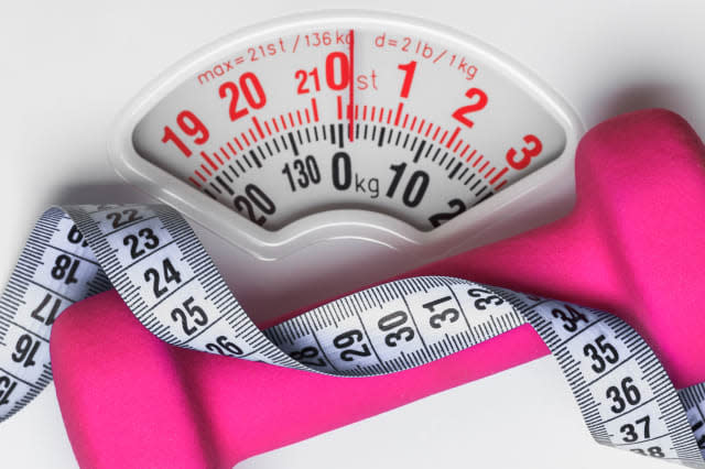 healthy lifestyle fitness weight control concept. Closeup pink dumbbell with measuring tape on white scales